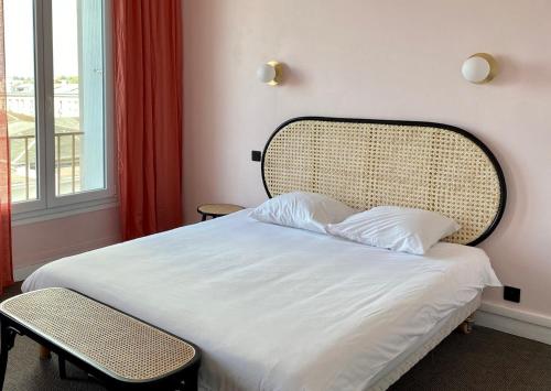 a bedroom with a bed with a rattan headboard and a window at Hotel Saint Louis in Brest