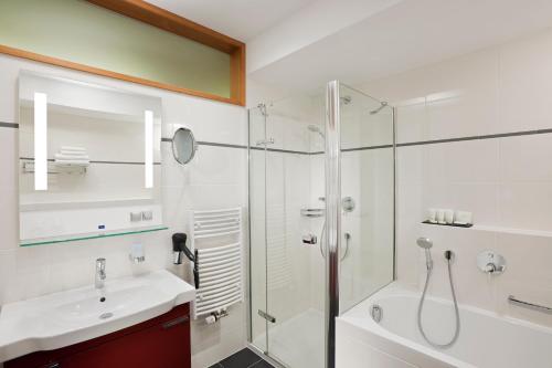 Vendryně的住宿－活力酒店，一间带玻璃淋浴、水槽和浴缸的浴室