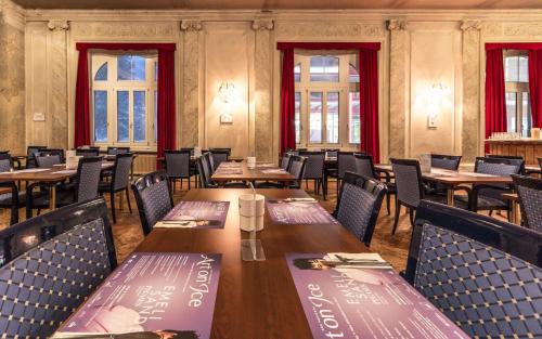 a restaurant with wooden tables and chairs and windows at Hotel Montana by Mountain Hotels in Davos