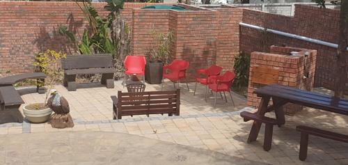 a patio with red chairs and a grill and benches at Bon A Vie Self-catering and b&b Gonubie Full Solar Power, no load shedding! in Gonubie