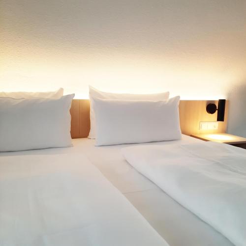 a large white bed with white pillows on it at Taste Hotel Hockenheim in Hockenheim