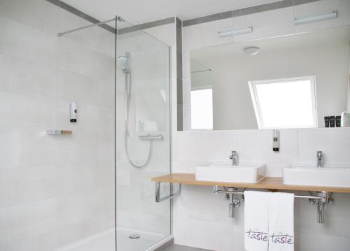 a bathroom with two sinks and a shower at Taste Hotel Hockenheim in Hockenheim
