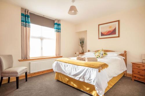 a bedroom with a bed and a chair and a window at Innes Street Apartments in Inverness