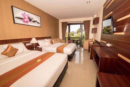 a hotel room with two beds and a television at Hotel Puri Nusa Indah in Denpasar