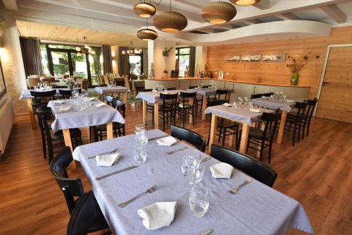 um restaurante com mesas e cadeiras com toalhas de mesa brancas em Hôtel et appart'hôtel de l'Hermitage em Thônes