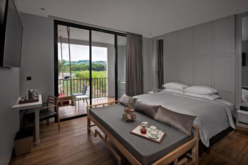 a bedroom with a bed and a table and a balcony at Sirinati Ban Thung Samo Khao Kho-Adults Only in Khao Kho