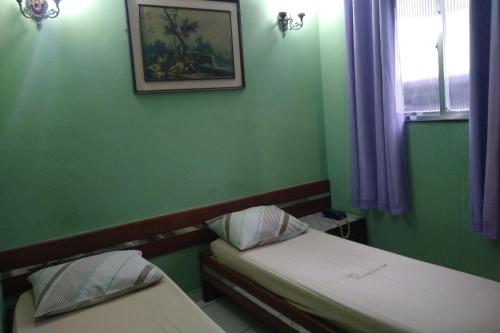 a green room with two beds and a window at Hotel Barão De Tefé in Rio de Janeiro