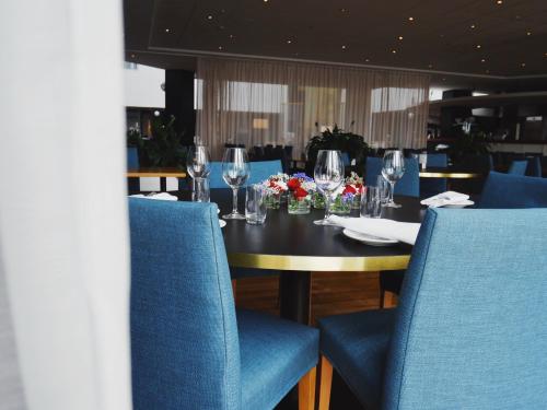 a dining table with blue chairs and wine glasses at Elite Hotel Marina Plaza in Helsingborg