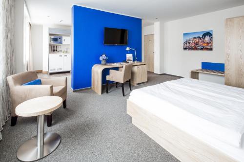 een slaapkamer met een blauwe muur en een bed en een bureau bij Hotel Global Inn in Wolfsburg