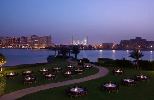 a group of tables and chairs on a lawn by the water at Fairmont Bab Al Bahr in Abu Dhabi