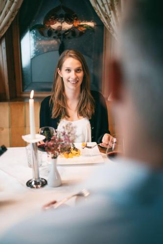 a woman sitting at a table with a plate of food at Wellnesshotel Warther Hof in Warth am Arlberg