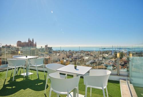 a patio area with chairs, tables, and umbrellas at Hotel Almudaina in Palma de Mallorca