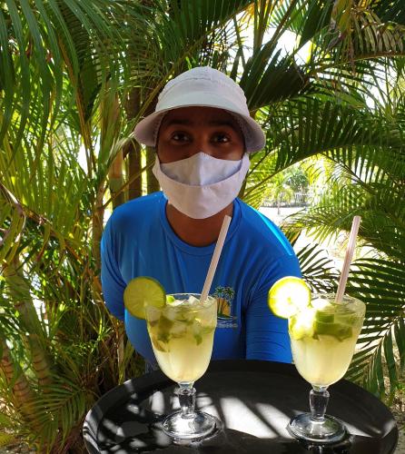 a man wearing a mask with two drinks on a table at Pousada o Forte in Mangue Sêco