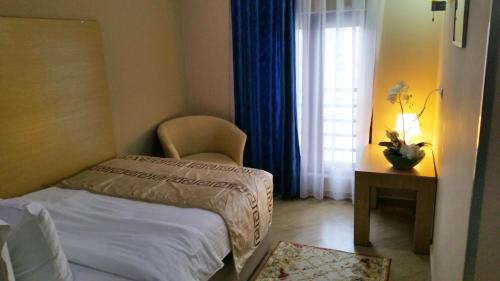 a bedroom with a bed and a chair and a table at Capital Tirana Hotel Bruçi in Tirana