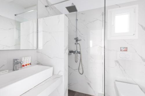a white bathroom with a shower and a sink at Sea Wind Apartments in Agios Stefanos