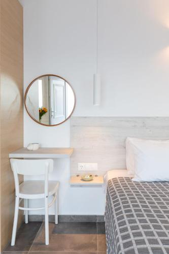 a bedroom with a bed with a mirror and a table at Sea Wind Apartments in Agios Stefanos