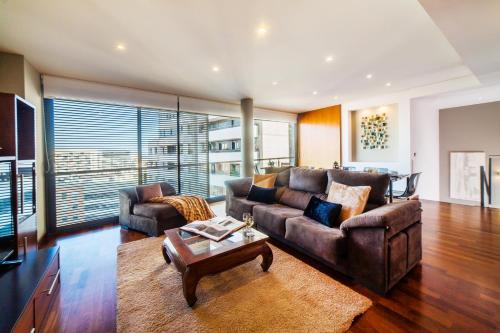 a living room with a leather couch and a table at Victoria Diagonal Mar Barcelona in Barcelona