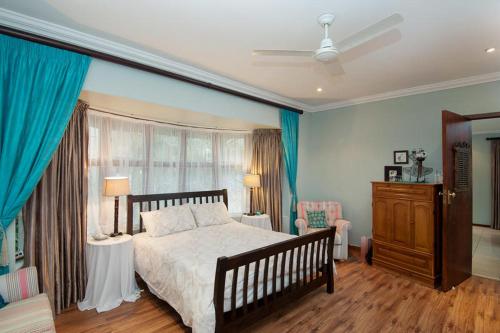 een slaapkamer met een groot bed met blauwe muren en blauwe gordijnen bij The Brother's Guest House in Durban