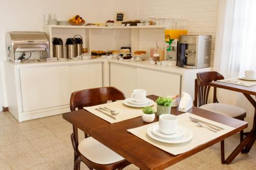 uma cozinha com uma mesa de madeira com cadeiras e um estofados de esteira em Pousada Lua Bella em Torres