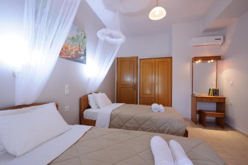 a hotel room with two beds and a desk at ELIAS & VASILI HOUSE in Agios Georgios Pagon