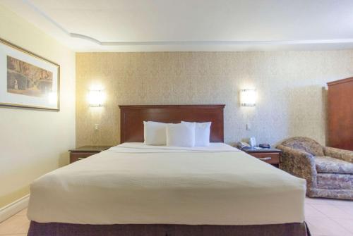 a hotel room with a large bed and a chair at Days Inn by Wyndham Shenandoah in The Woodlands