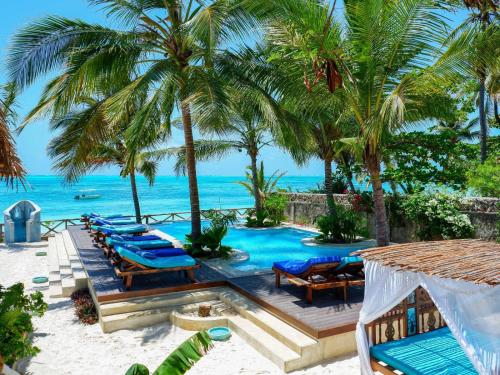 una piscina con sedie e palme sulla spiaggia di Casa Paradis a Jambiani