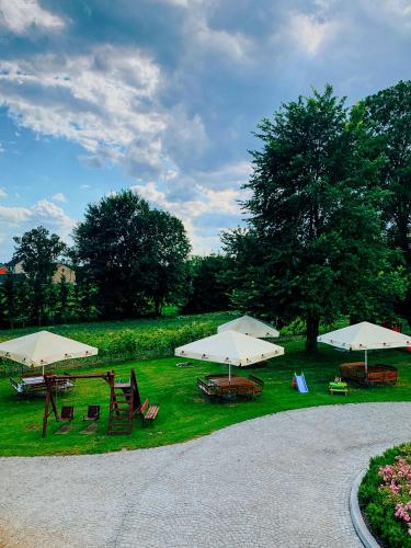 a group of tables with umbrellas on the grass at Dwór Karwacz in Przasnysz