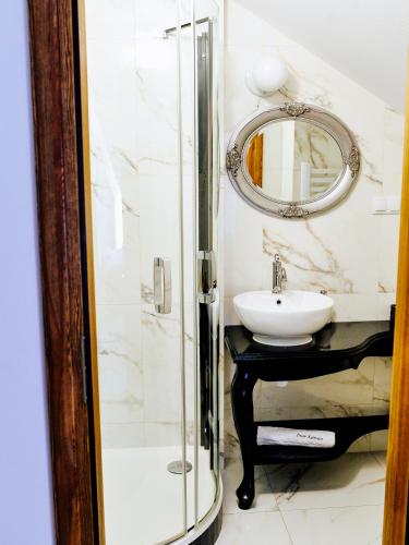 a bathroom with a sink and a shower with a mirror at Dwór Karwacz in Przasnysz
