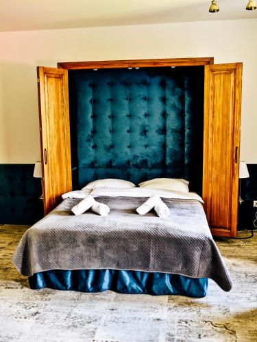 a bedroom with a large bed with a blue headboard at Dwór Karwacz in Przasnysz