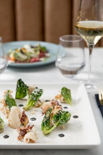 a plate of food on a table with a glass of wine at The Box Riccione - Adults Only in Riccione