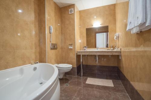 een badkamer met een bad, een toilet en een wastafel bij Aparthotel Poseidon in Sunny Beach