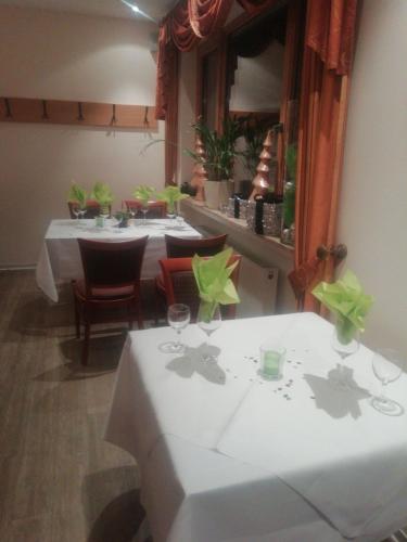 een eetkamer met twee tafels met groene bloemen erop bij Hotel Zur Mosel in Minheim