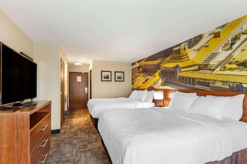 a hotel room with two beds and a flat screen tv at Clarion Pointe Racine - Mount Pleasant in Racine