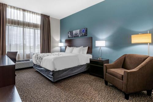 WaukeeにあるSleep Inn Waukee-West Des Moinesのベッドと椅子付きのホテルルーム