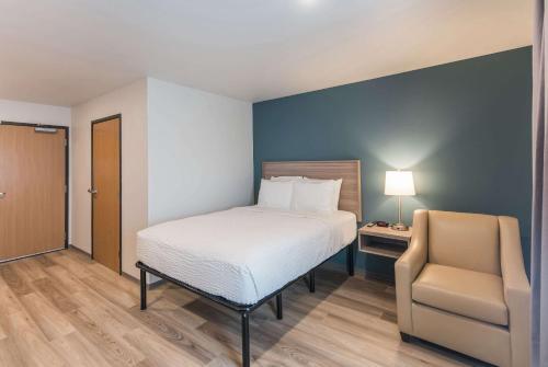 a bedroom with a bed and a chair and a desk at WoodSpring Suites Tri-Cities Richland in Richland