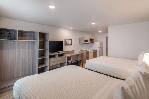 a bedroom with two beds and a desk with a television at WoodSpring Suites Tri-Cities Richland in Richland