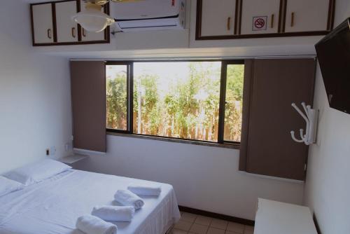 um quarto com uma cama e uma janela com toalhas em Guarajuba Summer Flat 10 em Guarajuba