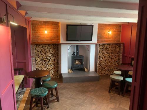a bar with a fireplace and stools and a tv at The White Horse in Cranswick