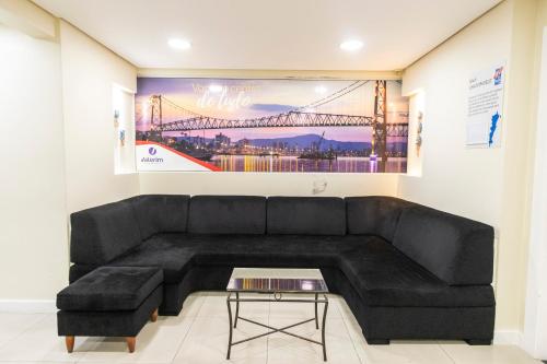 a living room with a black couch and a painting at Valerim Florianópolis in Florianópolis