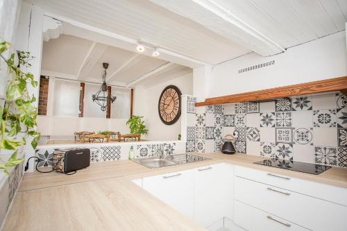 a kitchen with white cabinets and a clock on the wall at Le Grenier du Photographe in Kaysersberg