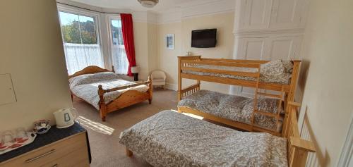 a room with two bunk beds and a television at sunnylodge in Folkestone