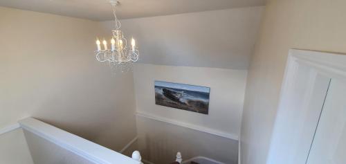 a chandelier in a white room with a staircase at sunnylodge in Folkestone