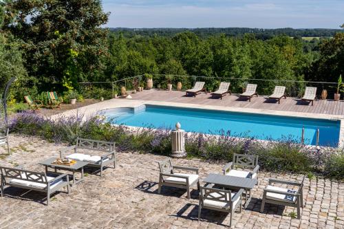 a swimming pool with chairs and a table next to it at Le Château des Forges in Angers