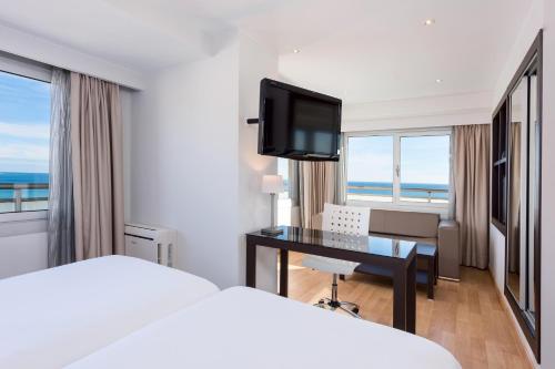 a hotel room with a bed and a desk and a television at Hotel Alicante Gran Sol, affiliated by Meliá in Alicante
