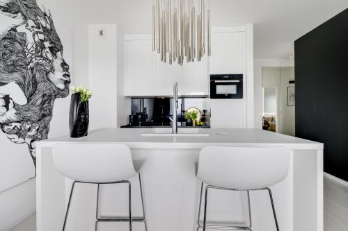 a kitchen with white counters and white stools at Apartamenty Tespis - Francuska Atal Park in Katowice