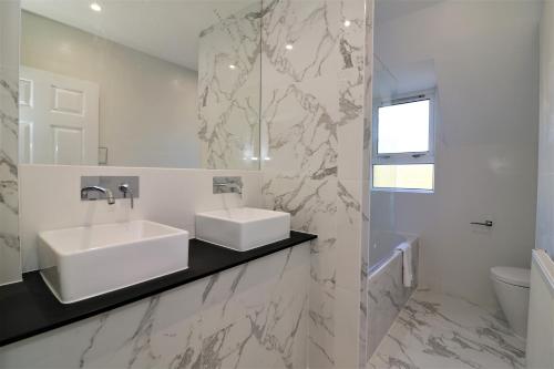 Baño blanco con lavabo y espejo en Jess View, en Renfrew