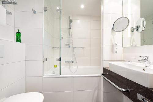 a white bathroom with a shower and a sink at Holiday Inn Berlin City East Side by IHG in Berlin