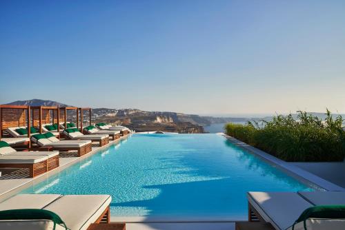 einen Pool mit Stühlen und Blick auf das Wasser in der Unterkunft Katikies Garden Santorini - The Leading Hotels Of The World in Fira