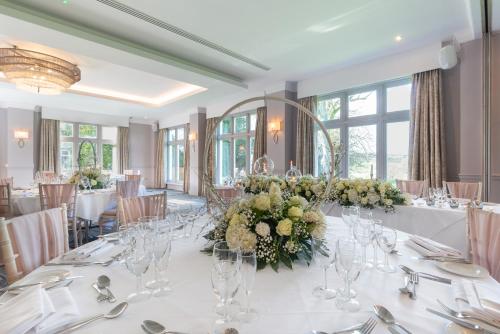 a dining room with a large white table with flowers at Mercure Blackburn Dunkenhalgh Hotel & Spa in Blackburn