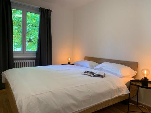 a bedroom with a large white bed with two lamps at Modern 2 bedroom apartment close to Zurich airport in Opfikon